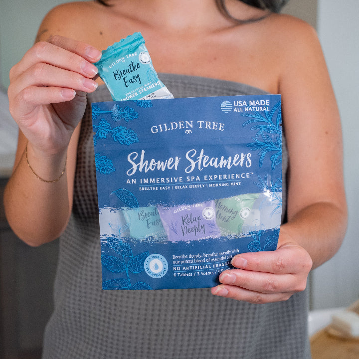 Person holding a package of Gilden Tree Shower Steamers with one open showing the product.