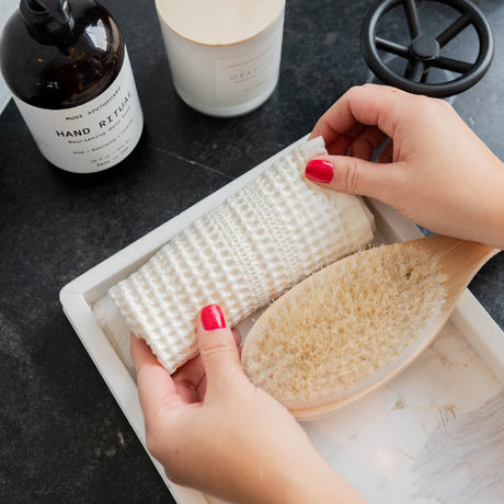 Cream waffle washcloth rolled on marble tray.