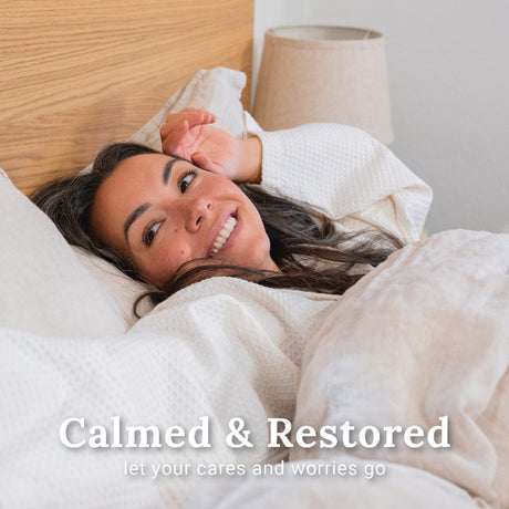 Woman laying in bed calmed and restored after using Relax Deeply shower steamers.