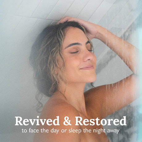 Woman under a shower with text 'Revived & Restored' on a light background
