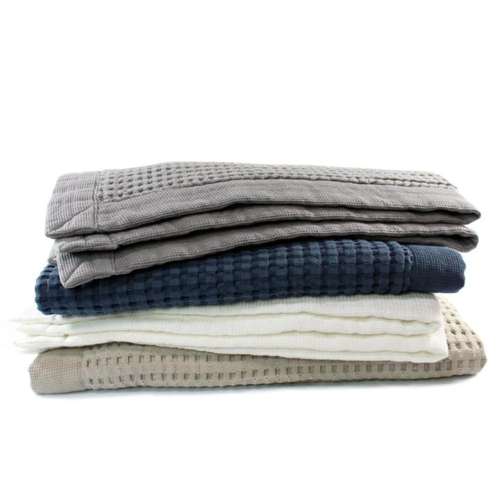 Waffle BathMats in a stack showing four colors:  Slate, Midnight, White and Pewter