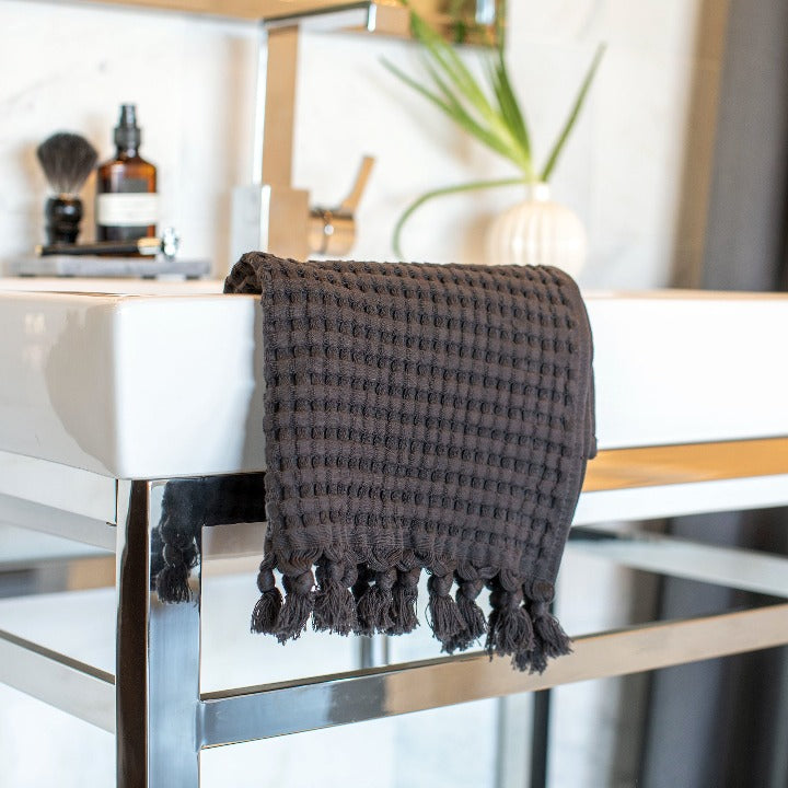 Faded black waffle weave tassel hand towel drapes elegantly on your sink